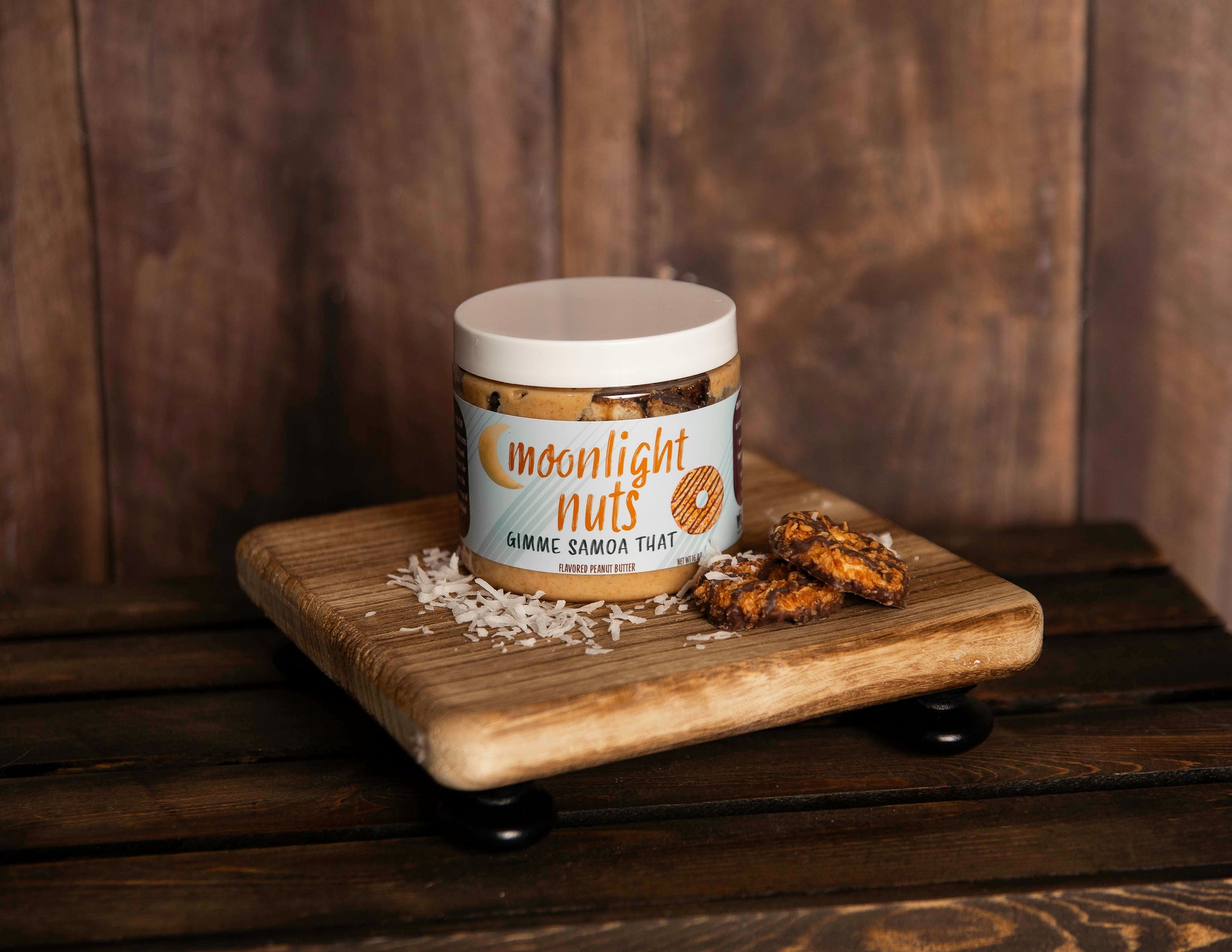 Moonlight Nuts Gimme Samoa That peanut butter jar with some of the toppings spread on a board around it.