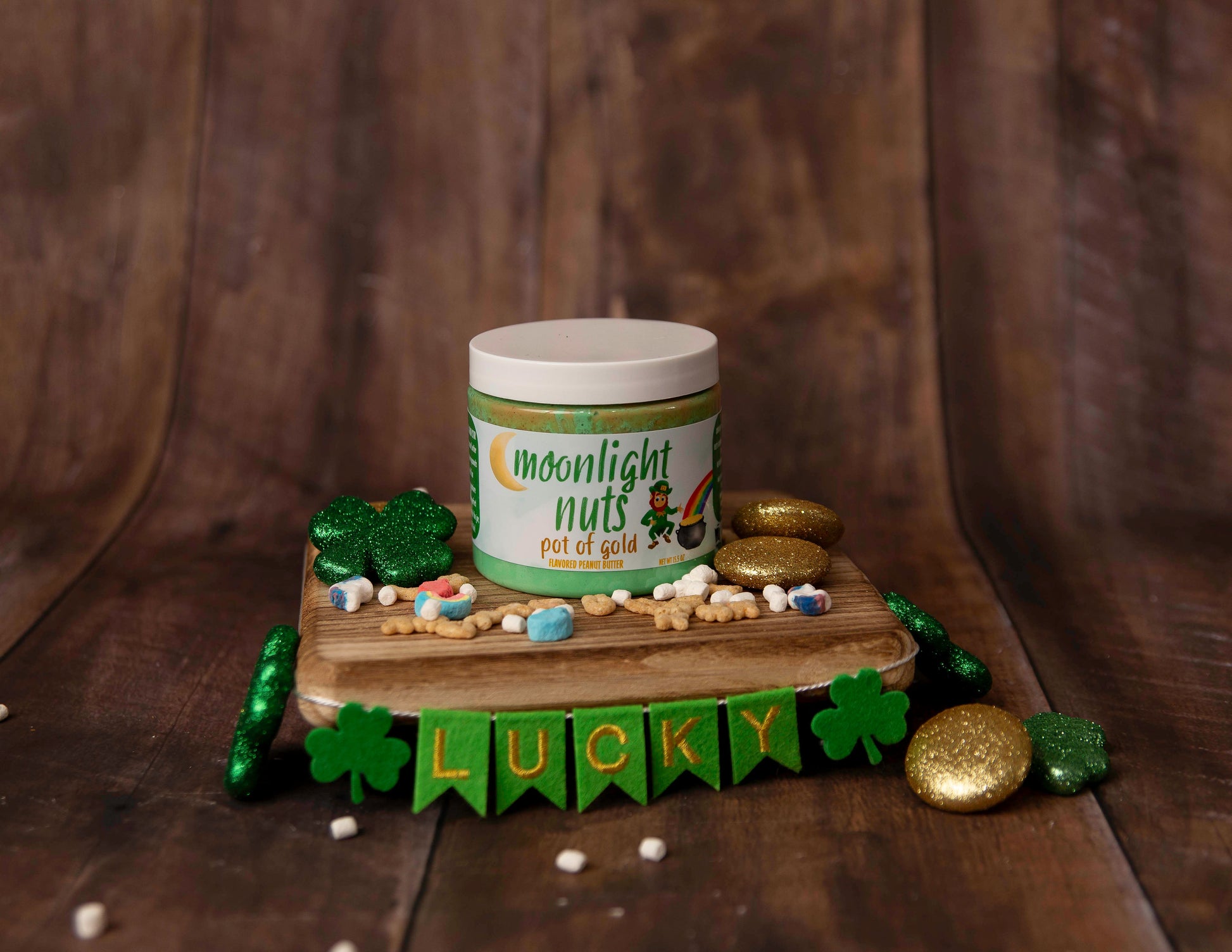 Jar of 'Moonlight Nuts Pot of Gold' on a wooden stand with gold and green elements on a brown background
