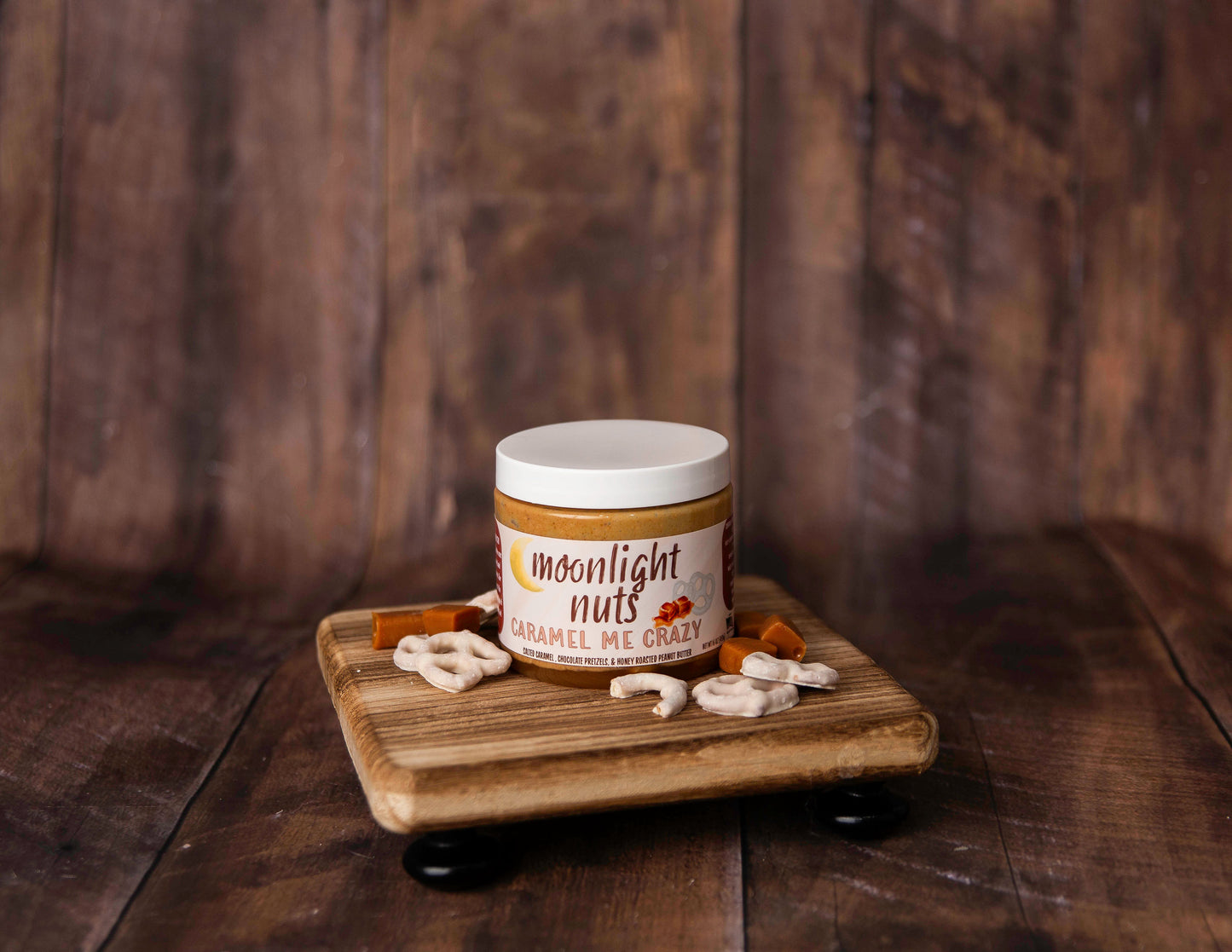 Jar of Moonlight Nuts Caramel Me Crazy small batch peanut butter on a wooden tray with a wooden background