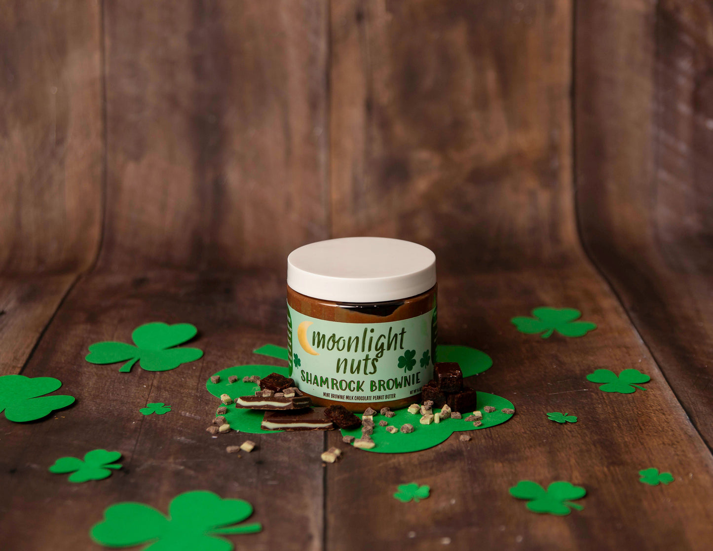 Jar of Moonlight Nuts Shamrock Brownie peanut butter showing some of the brownie and Andes mint toppings around it