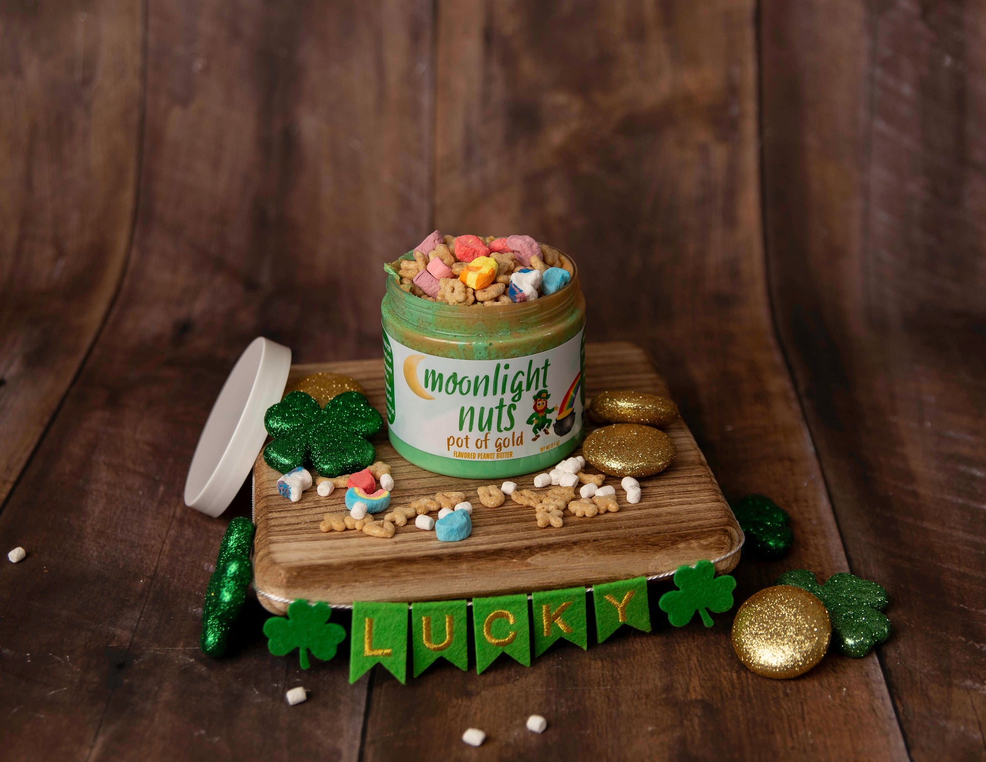 An open jar of Moonlight Nuts “Pot of Gold” lucky charms peanut butter showing the green marshmallow fluff, white chocolate peanut butter, and lucky charms.