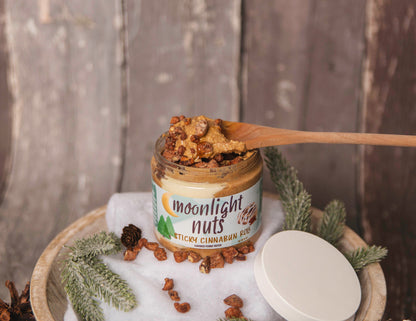 Jar of cinnamon roll peanut butter with spoon showing the texture and toppings 