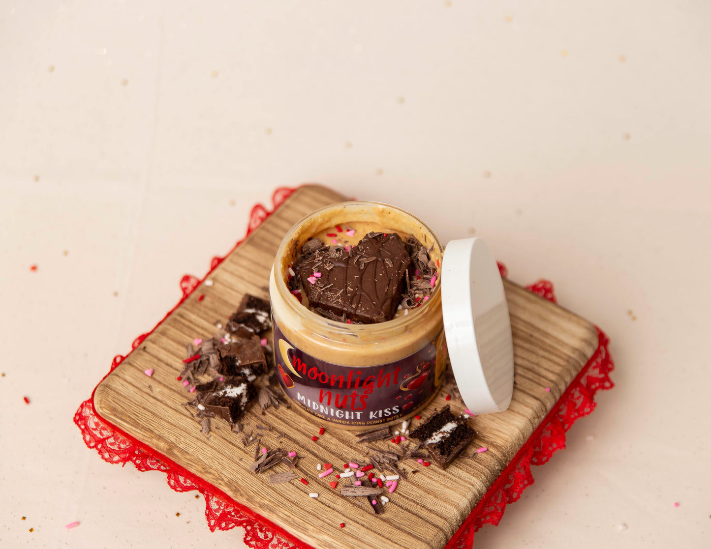 Jar of 'Moonlight Nuts Midnight Kiss' dessert peanut butter with sprinkles on a light surface.