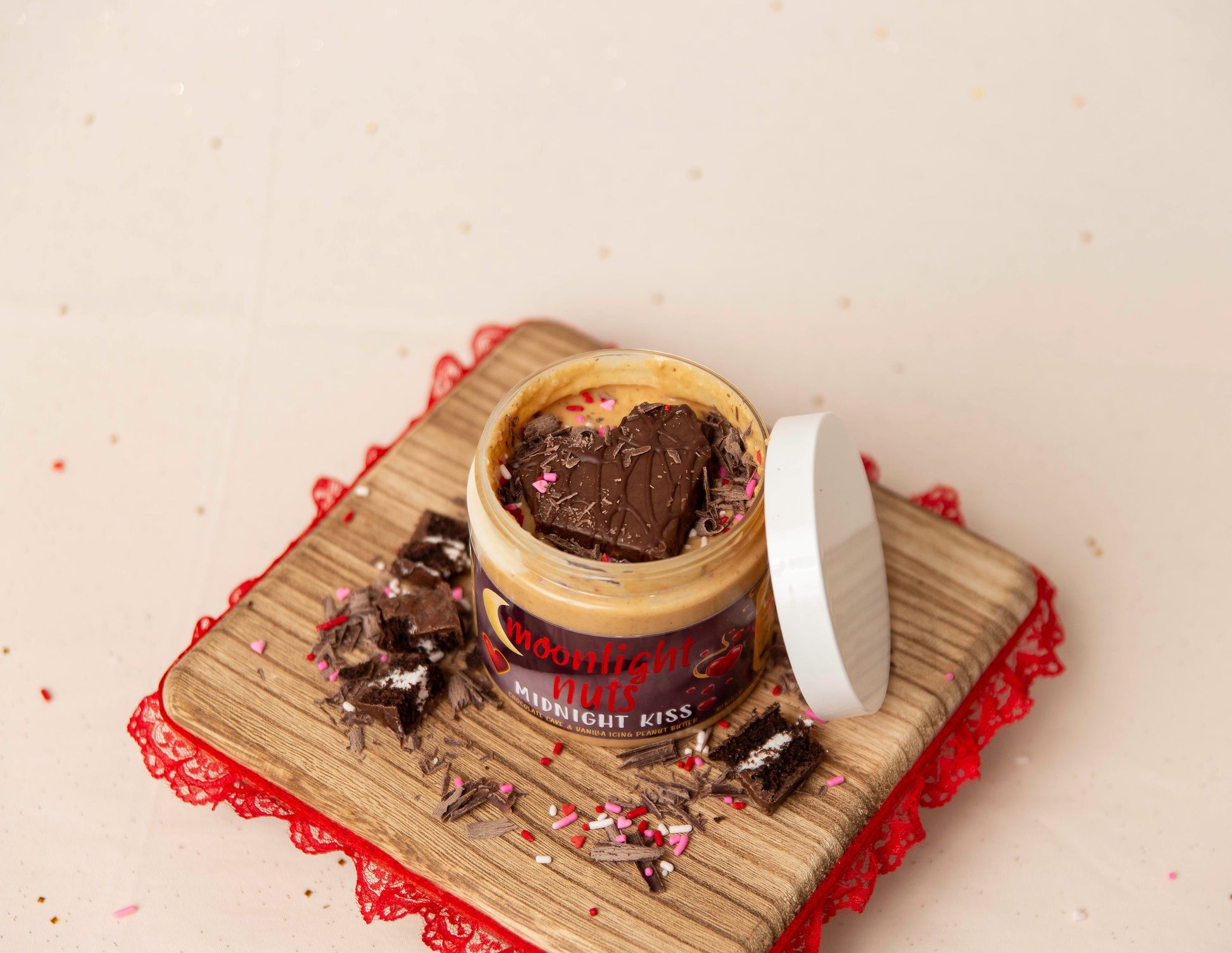 Jar of 'Moonlight Nuts Midnight Kiss' dessert peanut butter with sprinkles on a light surface.